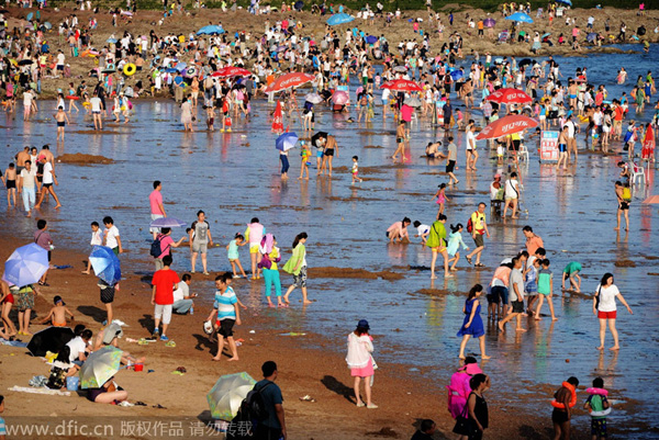 Bañistas se divierten en Golden Beach (Jinshatan) en Qingdao, una ciudad costera de la provincia de Shandong. Cientos de miles de bañistas se refrescan en el mar. 17 de agosto de 2014. [Foto/IC]