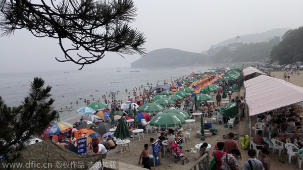Bañistas se divierten en una playa de Dalian, en la provincia de Liaoning. Los turistas siguen dispuestos a disfrutar de las playas, aunque el calor del veranose aleja y comienza el principio del otoño. 17 de agosto de 2014. [Foto/IC] 