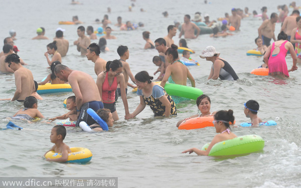 Bañistas se divierten en una playa de Dalian, en la provincia de Liaoning. Los turistas siguen dispuestos a disfrutar de las playas, aunque el calor del veranose aleja y comienza el principio del otoño. 17 de agosto de 2014. [Foto/IC] 