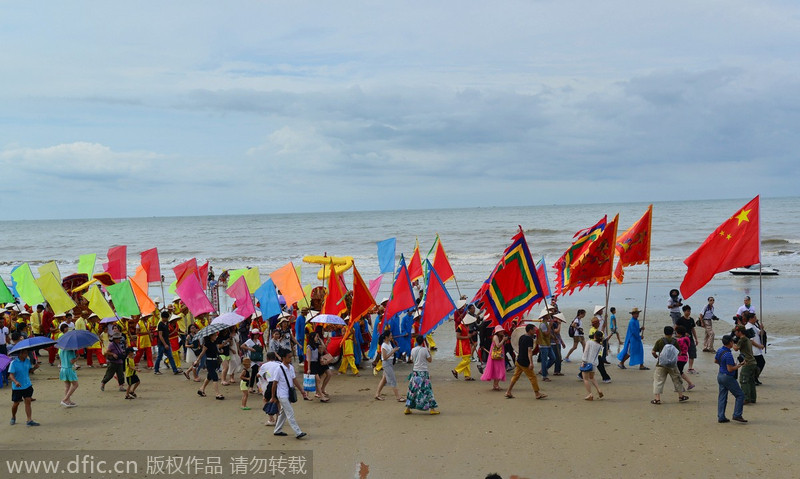Los Jing caminan a lo largo de la orilla para dar la bienvenida al dios del mar. 5 de julio de 2014. [Foto/IC]