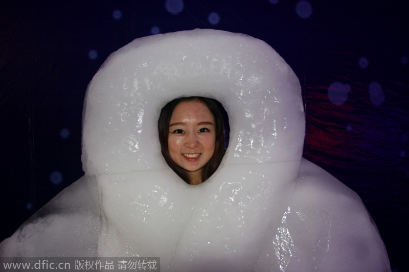 Una mujer posa para una foto detrás de una escultura de hielo en el Festival de Hielo y Nieve de Wuhan, en Hubei. De esta manera, el grupo Groenlandia publicita la promoción de sus propiedades durante el festival. 17 de agosto de 2014. [Foto/IC]