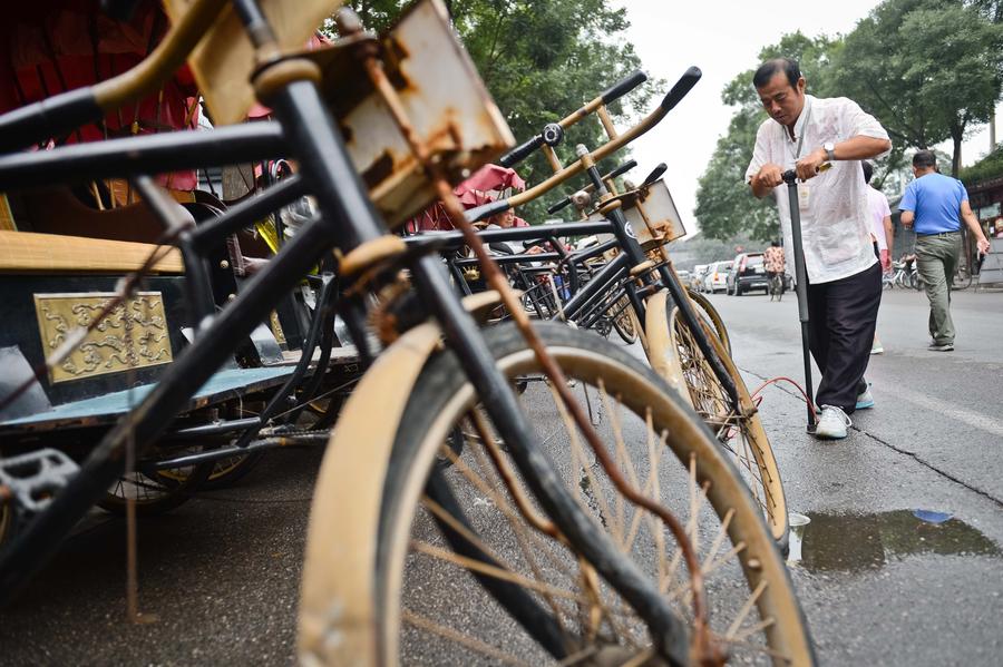 Cao Junlai infla la rueda de su rickshaw en Pekín, el 12 de septiembre de 2014.