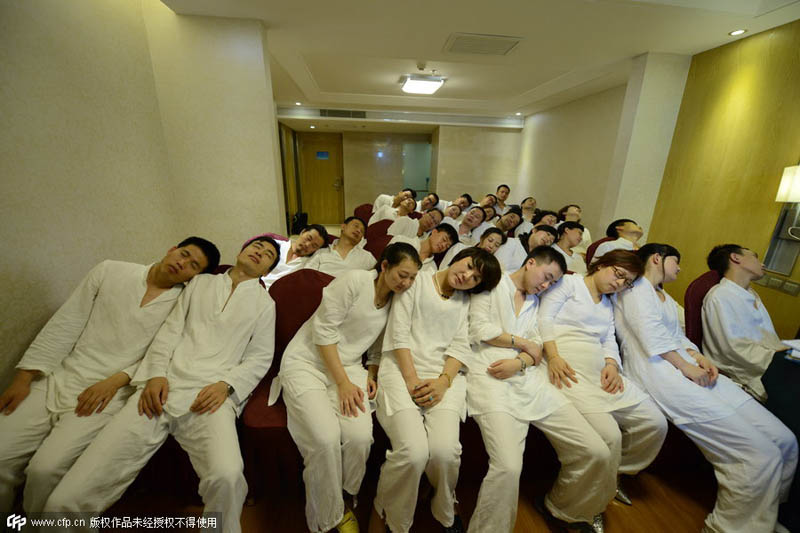 La gente asiste en pijama a una clase para aprender a descargar tensiones con una pequeña siesta en Changsha, provincia de Hunan, el 26 de mayo de 2014. [Foto / PPC]