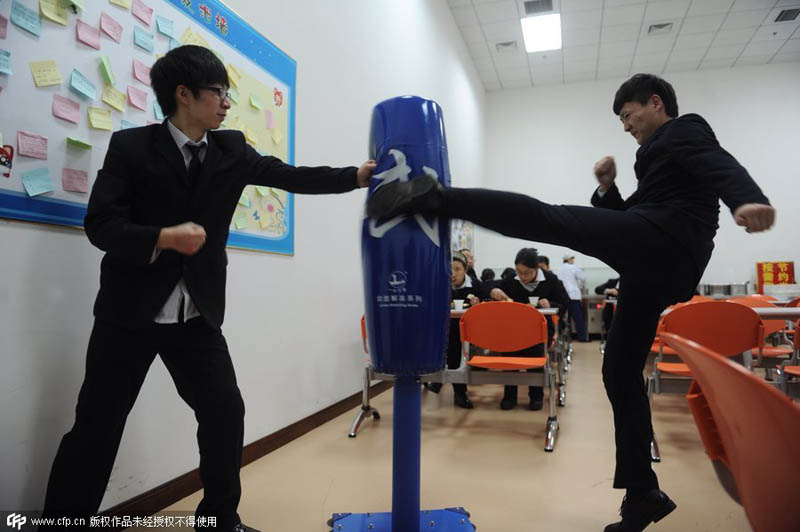 Trabajadores golpean un saco de boxeo en una compañía de Pekín, el 7 de enero de 2014. El saco lo instaló la empresa para que los trabajadores alivien su estrés. [Foto / PPC]