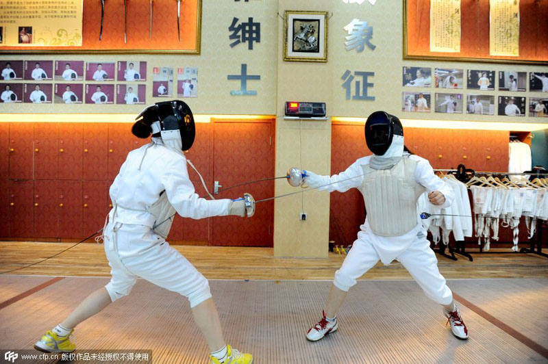 Dos compañeros de oficina practican esgrima para aliviar el estrés del trabajo, en Shenyang, provincia de Liaoning, el 21 de octubre de 2014. [Foto / PPC]