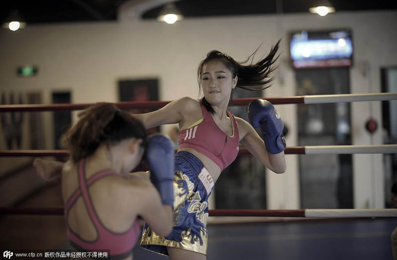 Dos compañeras boxean juntas en un club de boxeo tailandés de Chongqing para aliviar el estrés del trabajo, el 24 de agosto de 2014. [Foto / PPC]
