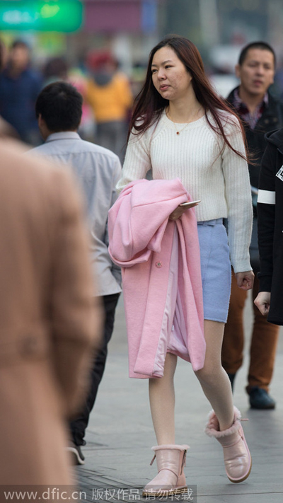 Una mujer se pasea con el abrigo en mano en Shanghai el 4 de enero de 2015. Las temperaturas subieron hasta los 15,6 grados en Shanghai el 4 de enero, la más alta de este invierno. [Foto/IC]