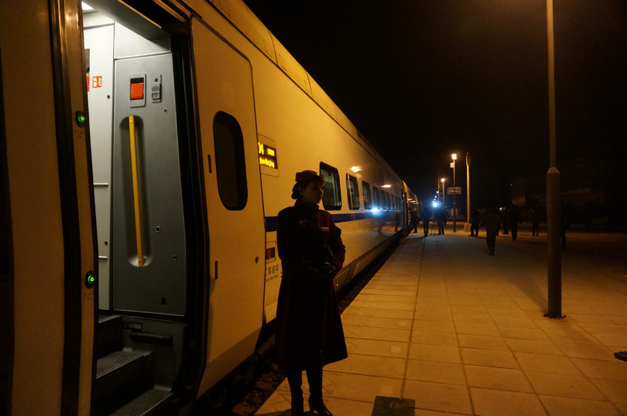 Una azafata del tren D9022 espera fuera el vagón en la estación de trenes de Yanjiao. El tren es el único de los tres trenes bala que sale por la mañana. [Fotografía de Zhang Xiang/chinadaily.com.cn]