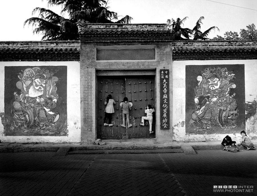 Los niños se suben a la puerta del templo Di Guan en Zhuxian del condado Kaifeng, provincia de Henan, el 2 de mayo de 2013. [Fotografía de Yin Ganjiang/photoint.net]