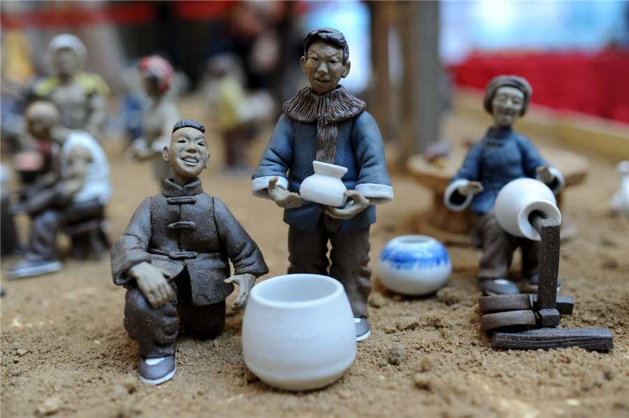 Estatuillas de unos artesanos vendiendo porcelana en la calle hechas de arcilla. [Fotografía por Wang Haibin/Asianewsphoto]