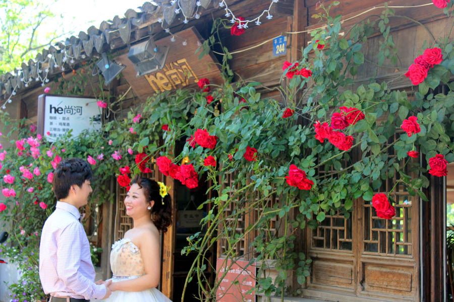 Una pareja hace sus fotos de boda delante de las rosas chinas en el camino Pingjiang, Suzhou, provincia de Jiangsu, el 5 de mayo de 2015. [Foto por Wang Jiankang / Asianewsphoto]