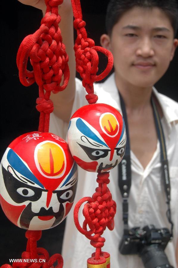 En Tancheng, provincia de Shandong,el artista Fan Yuye muestra sus trabajos de pintura sobre máscaras de la Ópera de Pekín en ornamentos. Máscaras de la ópera de Pekín se han convertido gradualmente en un elemento de moda en China. (Foto: Fang Dehua)