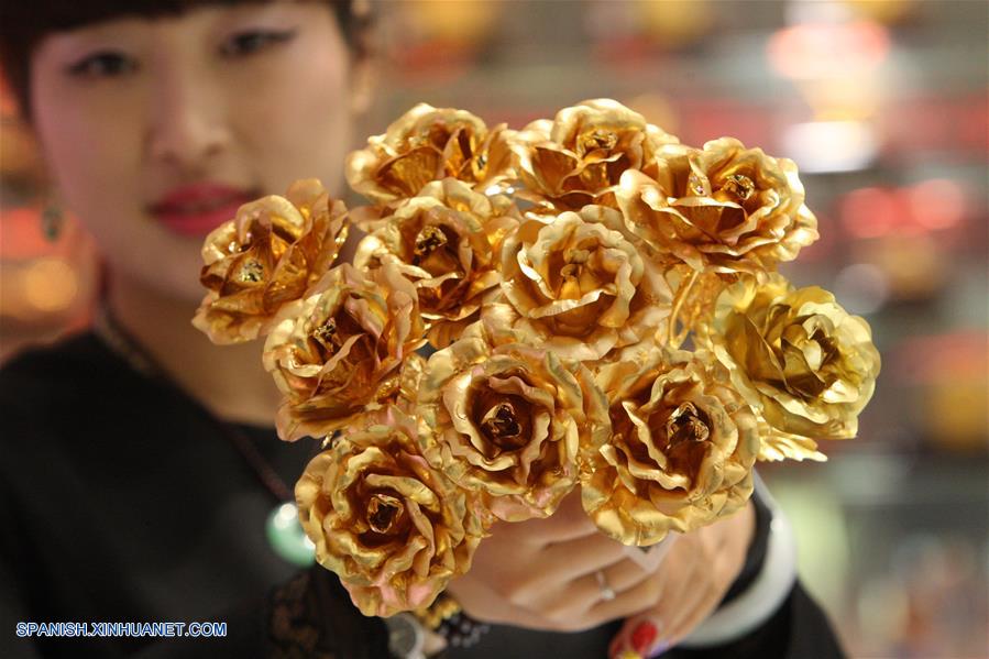 Una empleada muestra rosas doradas en una tienda en la ciudad de Yantai, Shandong provincia, el 12 de febrero de 2016. (Xinhua/Shen Jizhong)