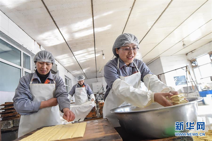 Bu (derecha) y sus empleados hacen cuajada de legumbres, el 23 de febrero de 2016.  El salario anual promedio de los empleados superó los 40.000 yuanes el año pasado, superior a la media nacional en las zonas rurales. [Foto/Xinhua]