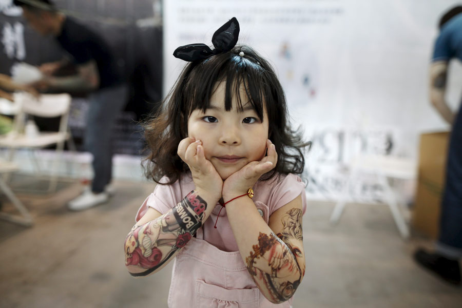 Candy Wang, de cuatro años, muestra sus tatuajes de pegatinas durante el Festival Internacional de los Tatuajes 2016 de Shanghai, el 23 de abril de 2016. [Foto/Agencias]