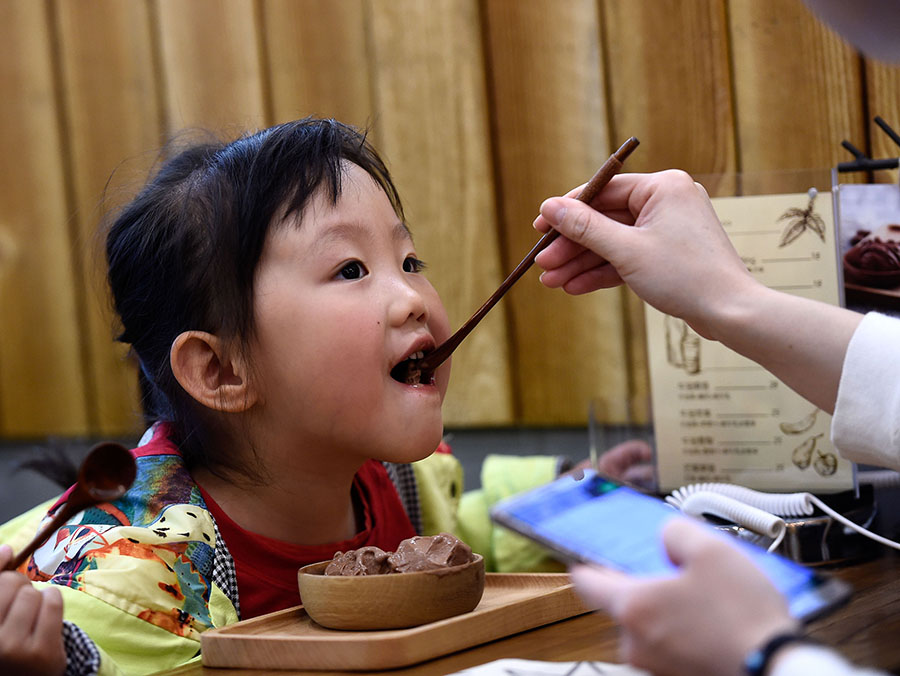 Una madre da a su hija pequeña un helado de la tienda de Cui en Taiyuan, provincia de Shanxi, el 26 de abril de 2016. [Foto/Xinhua]