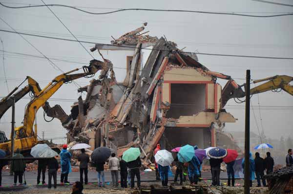 La gente observa la demolición de una casa en Wenling, provincia de Zhejiang, después de que su dueño llegara a un acuerdo con el gobierno local. [China Daily]