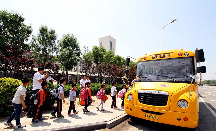Los alumnos de primaria hacen cola para subir a un autobús en Tianjin, el 17 de mayo de 2016. La ciudad ha puesto en circulación más de 30 autobuses escolares equipados con sistema de posicionamiento GPS para los estudiantes.