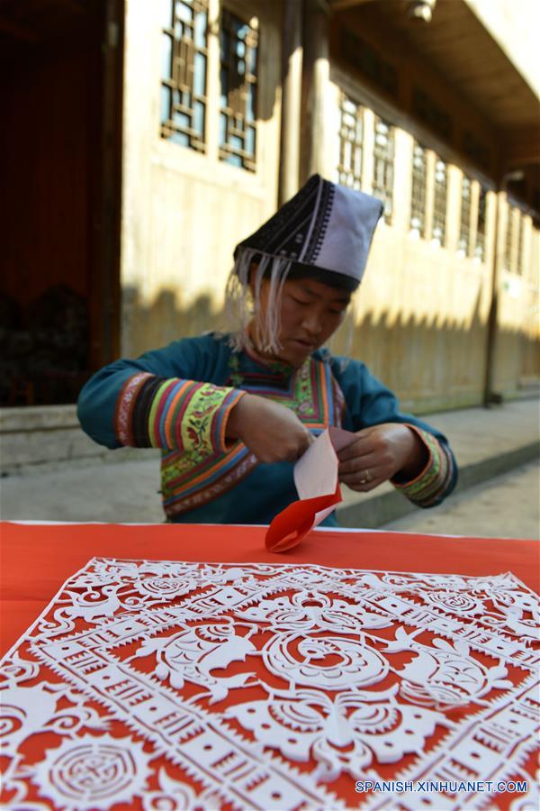 GUIZHOU, mayo 17, 2016 (Xinhua) -- Yang Xiuyue corta papel para elaborar una ropa tradicional de cien aves, en la villa Wuji, en el municipio de Tashi, del condado de Rongjiang, en la provincia de Guizhou, en el suroeste de China, el 16 de mayo de 2016. Las mujeres del grupo étnico miao que viven en la villa Wuji, ubicada en las remotas colinas del suroeste de China, maestras en sus bordados y batiks étnicos, que han sido enlistados por el gobierno de China como patrimonio cultural intangible. El gobierno local ha prestado mucha atención a la herencia de las habilidades tradicionales, promoviendo el sentido de protección y desarollo de mercados de los residentes. (Xinhua/Wang Bingzhen) 