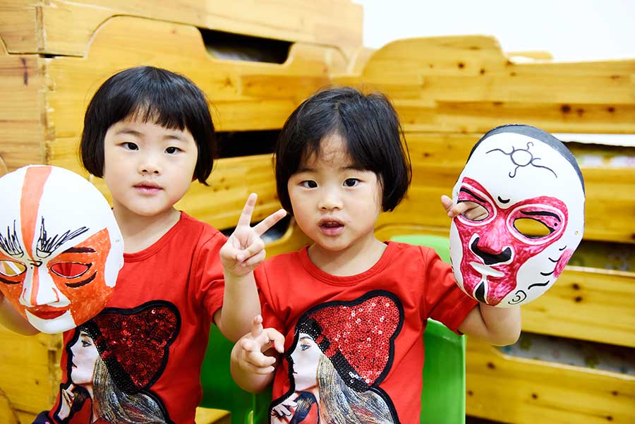 Dos niños muestran las máscaras faciales que hicieron de los personajes de la ópera de Pekín en la ciudad de Hefei, provincia de Anhui, el 3 de junio de 2016. [Foto de Ge Yinian/Asianewsphoto]