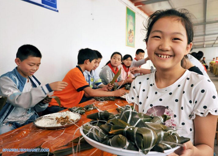 Estudiantes elaboran Zongzi, una bola de masa de arroz glutinoso envuelta en holas de bambú u hojas rojas, con motivo del próximo Festival del Bote de Dragón o Duanwu en chino, en Zaozhuang, provincia de Shandong, en el este de China, el 8 de junio de 2016. El Duanwu se celebrará el 9 de junio este año. (Xinhua/Li Zongxian)