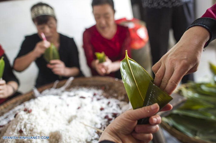 Personas elaboran Zongzi, arroz glutinozo colocado en hojas de bambú, para marcar el próximo Festival del Bote del Dragón, en el condado Zigui, capital de la provincia central de Hubei, China, el 8 de junio de 2016. El Festival del Bote de Dragón o "Duanwu" en chino, se celebra el quinto día del quinto mes del calendario lunar, celebrándose este año el 9 de junio. (Xinhua/Xiao Yijiu)