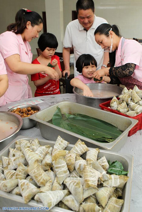 Niños así como sus maestros elaboran Zongzi, una bola de masa de arroz glutinoso envuelta en holas de bambú u hojas rojas, con motivo del próximo Festival del Bote de Dragón o Duanwu en chino, en una casa de caridad en Xuchang, provincia de Henan, en el centro de China, el 8 de junio de 2016. El Duanwu se celebrará el 9 de junio este año. (Xinhua/Niu Shupei)