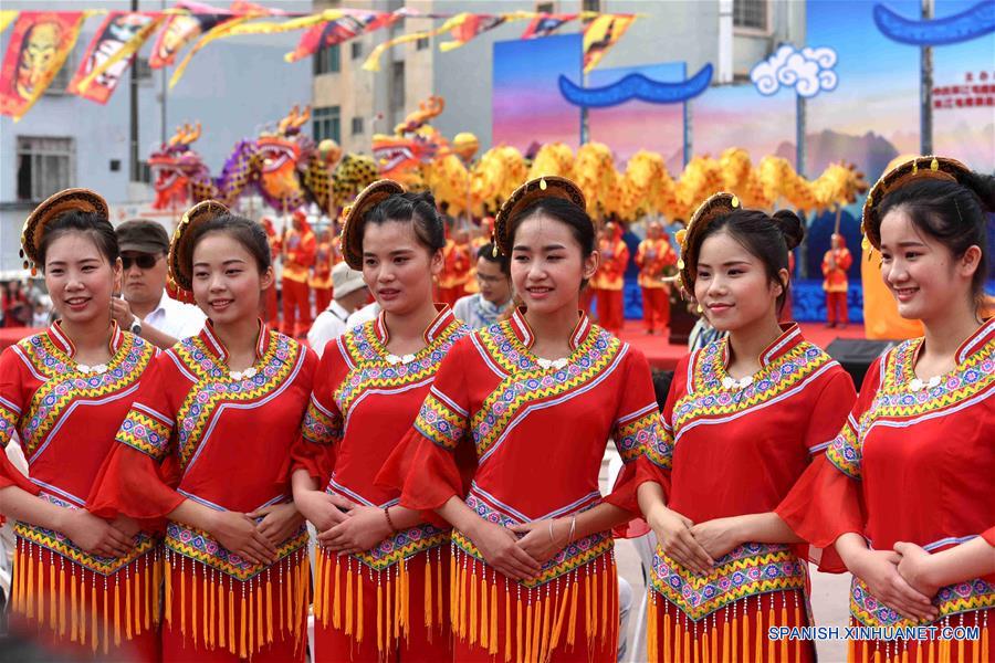 Mujeres usan un traje tradicional del grupo étnico de Maonan, mientras saludan a los visitantes durante el festival fenlong, en el condado de Huanjiang, en la Región Autónoma Zhuang de Guangxi, en el sur de China, el 18 de junio de 2016. El evento contará con actividades de baile, festival de comida, concursos de bote dragón, y actividades de canto. Los aldeanos del grupo étnico Maonan, festejan su festival anual para orar por la cosecha. (Xinhua/Gao Dongfeng)