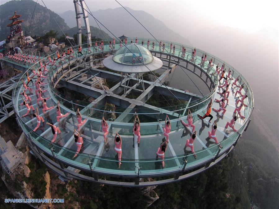 Personas practican yoga en una plataforma de cristal en Beijing