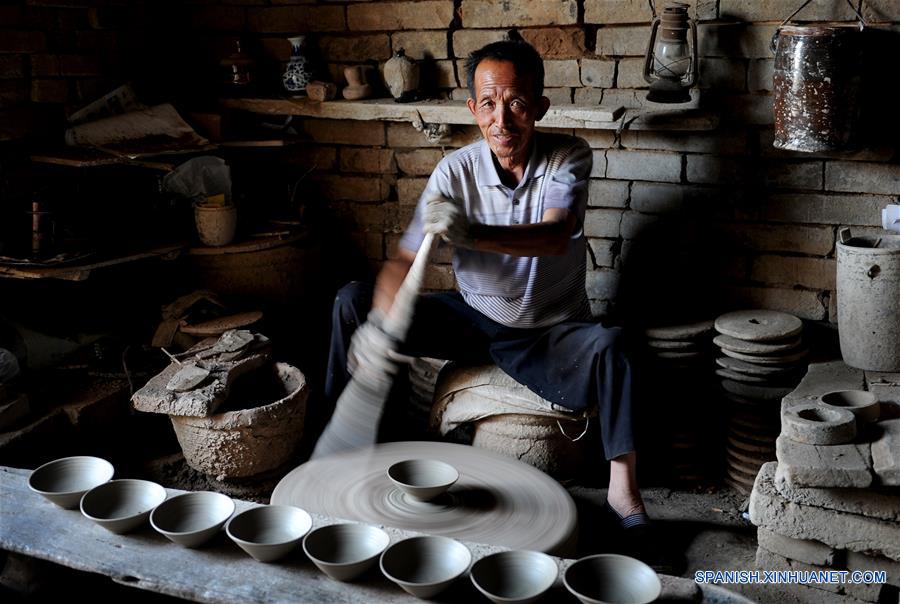 Imagen del 28 de junio de 2016 del artista folclórico Zhou Tiehuai elaborando cuencos de porcelana en bruto, en la zona turística de Yaotou Kiln en el municipio de Yaotou del condado de Chengcheng, provincia de Shaanxi, en el noroeste de China. El sitio de antiguos hornos populares, cubriendo un área de cuatro kilómetros cuadrados, tiene una historia de elaboración de productos de cerámica de más de mil años. La técnica de elaboración de cerámica en Yaotou Kiln fue incluida en el Patrimonio Nacional Cultural Intangible en el 2006. (Xinhua/Tao Ming)