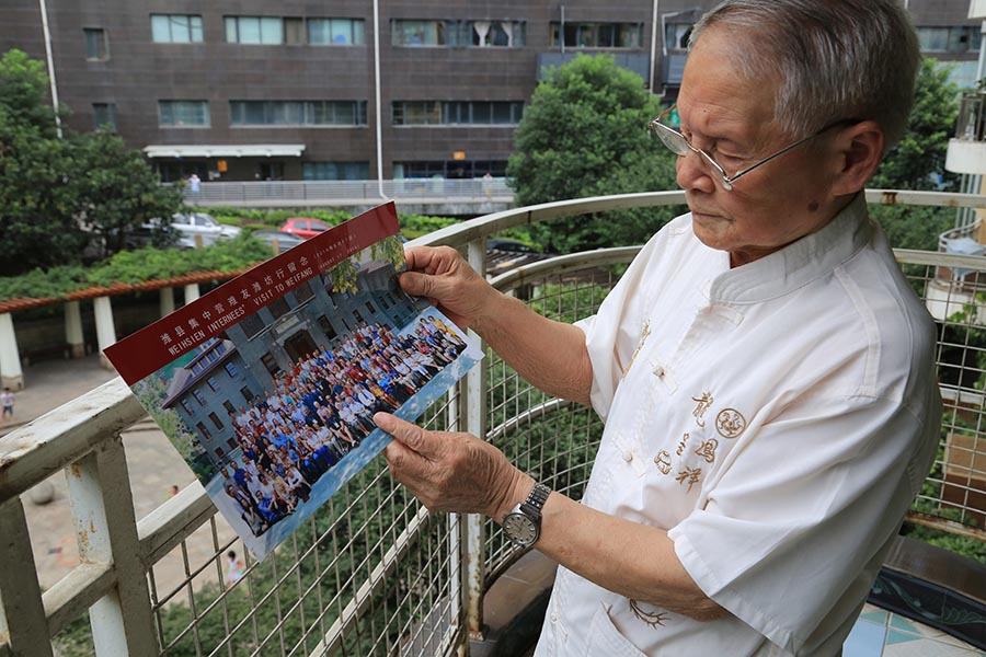 Wang mira la foto de los internados que él ayudó a liberar hace 71 años. [Fotografía de Jun/chinadaily.com.cn Yang]