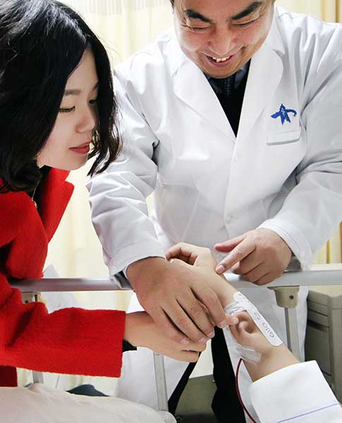 Guo Shuzhong, experto en cirugía reconstructiva del Hospital de la Universidad Jiaotong de Xian, comprueba la oreja que crece en el brazo de un paciente, que perdió su oreja derecha en un accidente de coche, el miércoles. [Ruan Banhui / China Daily]