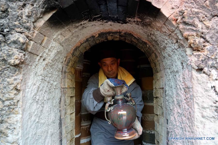 Un miembro del personal saca un artículo Jun de alfarería durante una ceremonia de retiro de porcelanas del horno, en el municipio de Shenhou de la ciudad de Yuzhou, provincia de Henan, en el centro de China, el 19 de noviembre de 2016. La porcelana Jun es famosa por su asobroso cambio de color durante el proceso de fundido en hornos. Shenhou, una localidad antigua ubicada en la zona montañosa de Henan, tiene una larga historia de elaboración de porcelana Jun. (Xinhua/Li An)