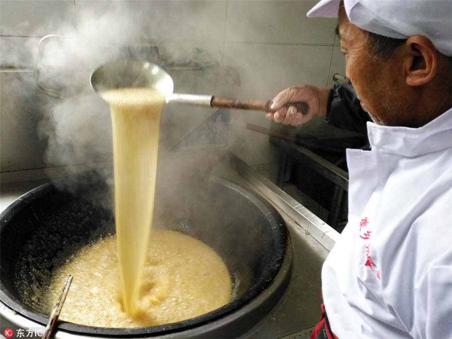 Un maestro de dulces tradicionales hierve jarabe de maltosa para realizar el tradicional caramelo de frijoles, fundamental en el sabor del Zi Dou Tang. 