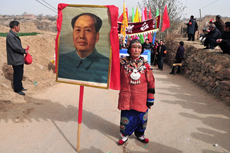 Una anciana muestra un retrato de Mao Zedong que está ubicado en un templo de Ruicheng, provincia de Shanxi. [Foto: IC]