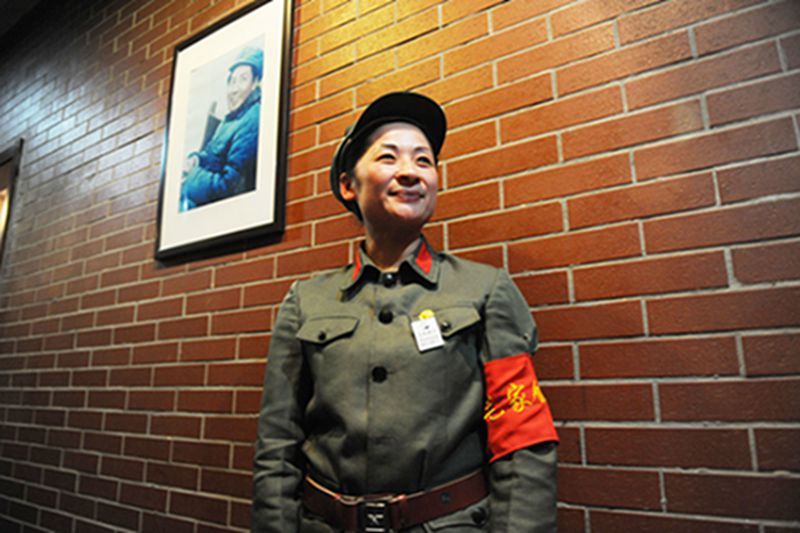 Camarera con un uniforme de la guardia roja saluda a los clientes delante de una foto de Mao Zedong en el restaurante Mao ubicado en Bozhou, provincia de Anhui. [Foto: IC]