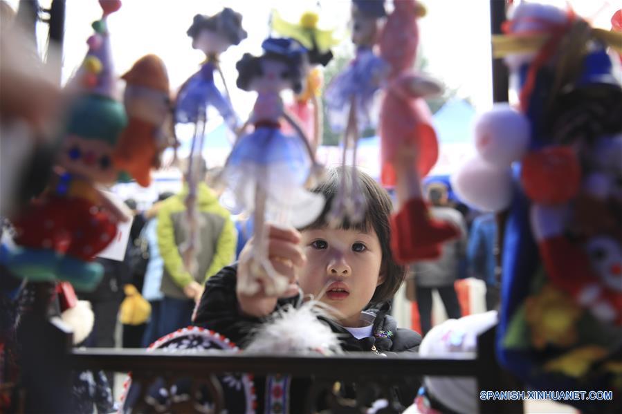 Una niña observa las muñecas en una feria durante las vacaciones de Año Nuevo, en Chongqing, en el suroeste de China, el 31 de diciembre de 2016. (Xinhua/Qin Tingfu)