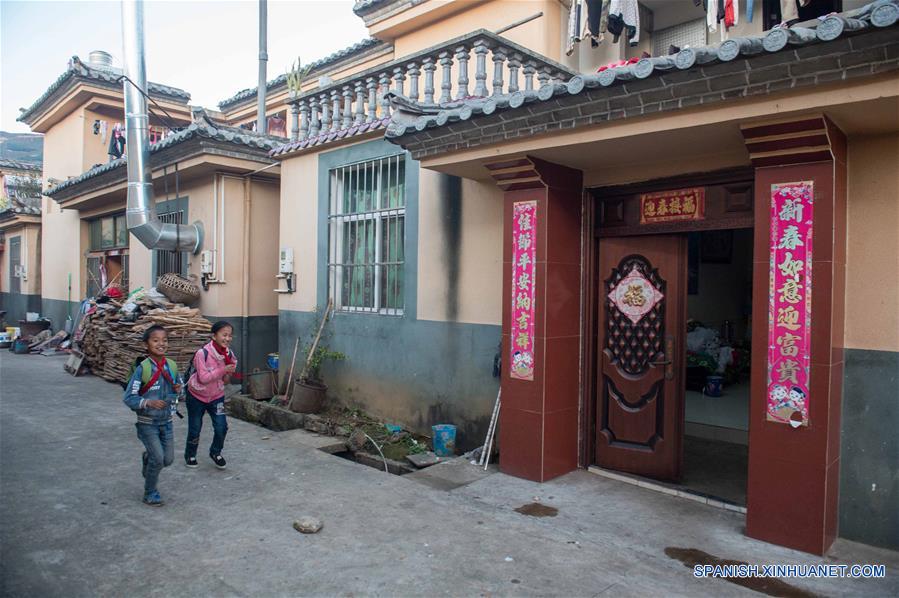 Unos niños pasan por su casa recientemente construida en el distrito de Mojiang el 12 de enero del presente año.  