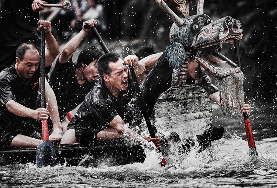 Los participantes de una carrera de botes de dragón se esfuerzan remando en un barco. Foto de Chu Yongfeng. [Foto proporcionada por photoint.net]
