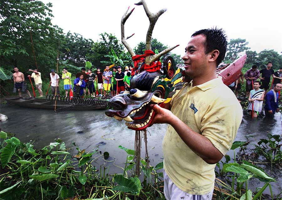 Varias personas trasladan un bote de dragón al río. Foto de Luo Pingxi. [Foto proporcionada por photoint.net]