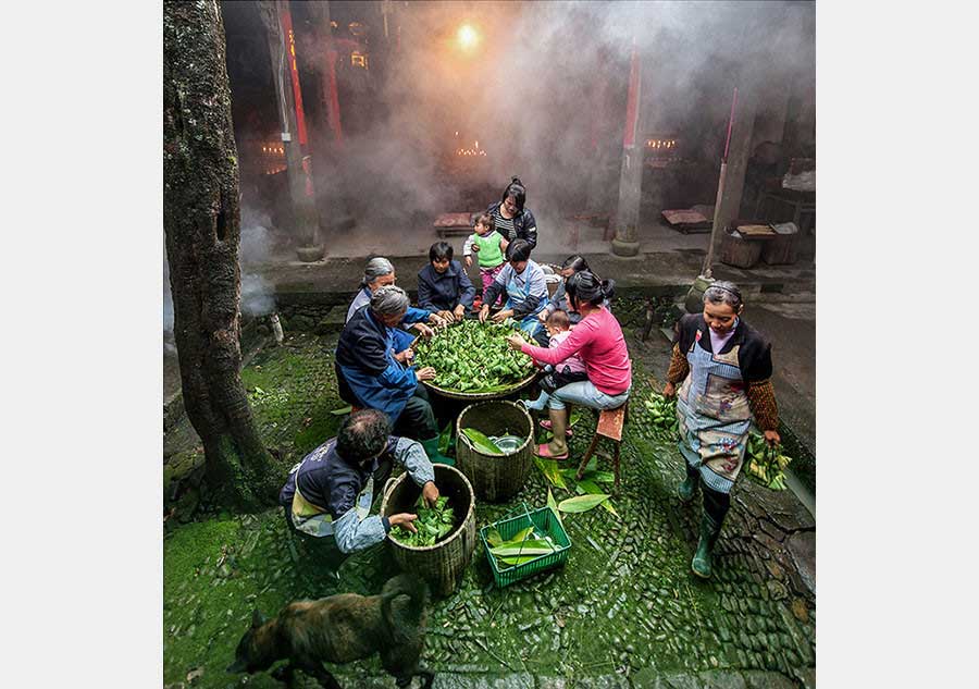 Los ancianos preparan zongzi, un aperitivo en forma de pirámide hecho de bola de arroz glutinoso relleno y envuelto en hojas de bambú o caña, durante el Festival del Bote de Dragón. Foto de Zhang Yougang. [Foto proporcionada por photoint.net]
