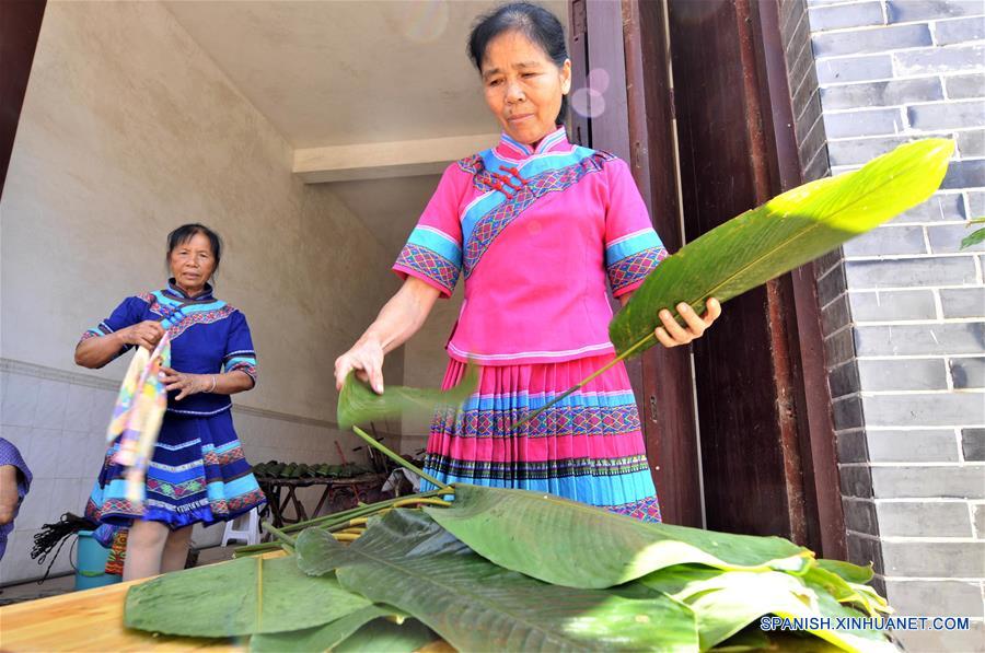 NANNING, mayo 29, 2017 (Xinhua) -- Imagen del 28 de mayo de 2017, de una mujer del grupo étnico Zhuang elaborando un "zhongzi" con forma de almohada, en el municipio de Luobo en el distrito de Wuming de Nanning, en la Región Autónoma Zhuang de Guangxi, en el sur de China. El "zongzhi"con forma de almohada en Luobo es elaborado con arroz glutinoso y carne. (Xinhua/Pan Huanqing)