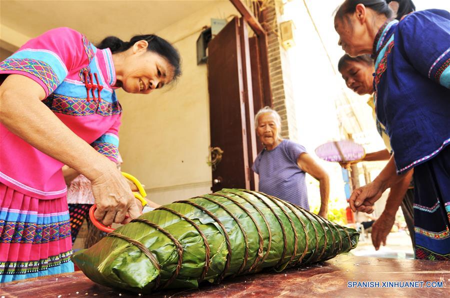 NANNING, mayo 29, 2017 (Xinhua) -- Imagen del 28 de mayo de 2017, de mujeres del grupo étnico Zhuang elaborando un "zhongzi" con forma de almohada en el municipio de Luobo en el distrito de Wuming de Nanning, en la Región Autónoma Zhuang de Guangxi, en el sur de China, el 29 de mayo de 2017. El "zongzhi"con forma de almohada en Luobo es elaborado con arroz glutinoso y carne. (Xinhua/Pan Huanqing)