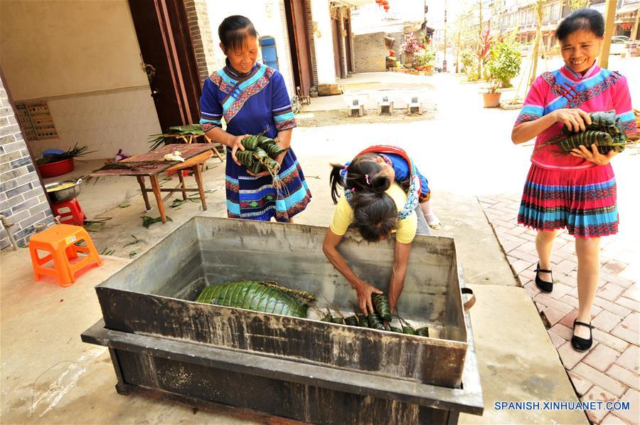 NANNING, mayo 29, 2017 (Xinhua) -- Imagen del 28 de mayo de 2017, de mujeres del grupo étnico Zhuang introduciendo "zhongzi" con forma de almohada en una caldera en el municipio de Luobo en el distrito de Wuming de Nanning, en la Región Autónoma Zhuang de Guangxi, en el sur de China, el 29 de mayo de 2017. El "zongzhi"con forma de almohada en Luobo es elaborado con arroz glutinoso y carne. (Xinhua/Pan Huanqing)
