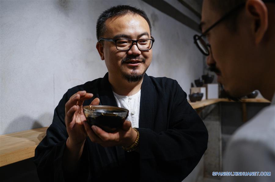 Cao Qingli (i), un artesano de la ciudad de Liuzhou, muestra sus obras a visitantes en el Museo True Color en Suzhou, en la provincia de Jiangsu, en el este de China, el 29 de mayo de 2017. La exhibición muestra más de 90 obras de "juci", una técnica tradicional de arreglar porcelana con grapas. Estará abierta hasta el 31 de diciembre. (Xinhua/Li Xiang)