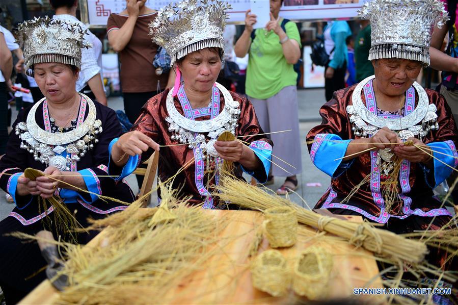 Mujeres Dong muestran cómo elaborar Caolong, dragón hecho con paja de arroz pegajosa para ser tejida en los festivales, durante una exhibición de patrimonio cultural en Longsheng, en la Región Autónoma Zhuang de Guangxi, en el sur de China, el 9 de junio de 2017. (Xinhua/Li Xuanli)  