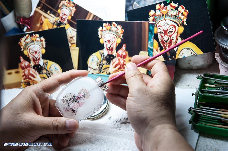 Imagen del 18 de julio de 2017 de Dong Xue, un artista de pintura interior, creando una botella de vidrio de tabaco pintada en el interior, en su vivienda en Shijiazhuang, capital de la provincia de Hebei, en el norte de China. La botella de tabaco de vidrio pintada en el interior es una artesanía tradicional china. El arte de pintura interior, que tiene una historia de más de 200 años, fue inscrita también como uno de los patrimonios culturales nacionales intangibles. Dong Xue y su hija han continuado estudiando la técnica y decidieron transmitirla. (Xinhua/Pu Dongfeng)