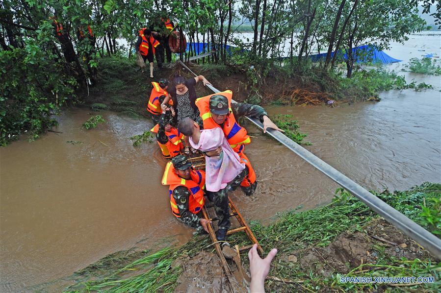 Bomberos rescatan a pobladores en la aldea Bajiapu, en el condado de Xiuyan de Anshan, en la provincia de Liaoning, en el noreste de China, el 4 de agosto de 2017. Una lluvia torrencial afectó al condado el jueves y viernes, dañando caminos, instalaciones de electricidad y cultivos en algunos municipios. Un total de 18,900 personas han sido trasladadas a lugares seguros, y la ciudad ha iniciado el nivel 1 de respuesta de emergencias para enfrentar las posibles inundaciones. (Xinhua/Yang Qing)