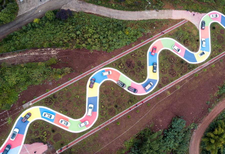 El 18 de noviembre de 2017, varios vehículos circulan por una carretera en forma de serpiente en Chongqing, sudoeste de China. La calle de 185 metros con superficie colorida entró en funcionamiento como lugar de ocio. [Foto / VCG]