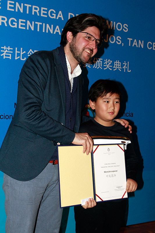 Guillermo Bravo, profesor y escritor argentino residente en Beijing, entrega una mención especial a un niño chino durante la premiación del primer concurso literario “Argentina: tan lejos, tan cerca”. Beijing, 21 de noviembre del 2017. (Foto: YAC)